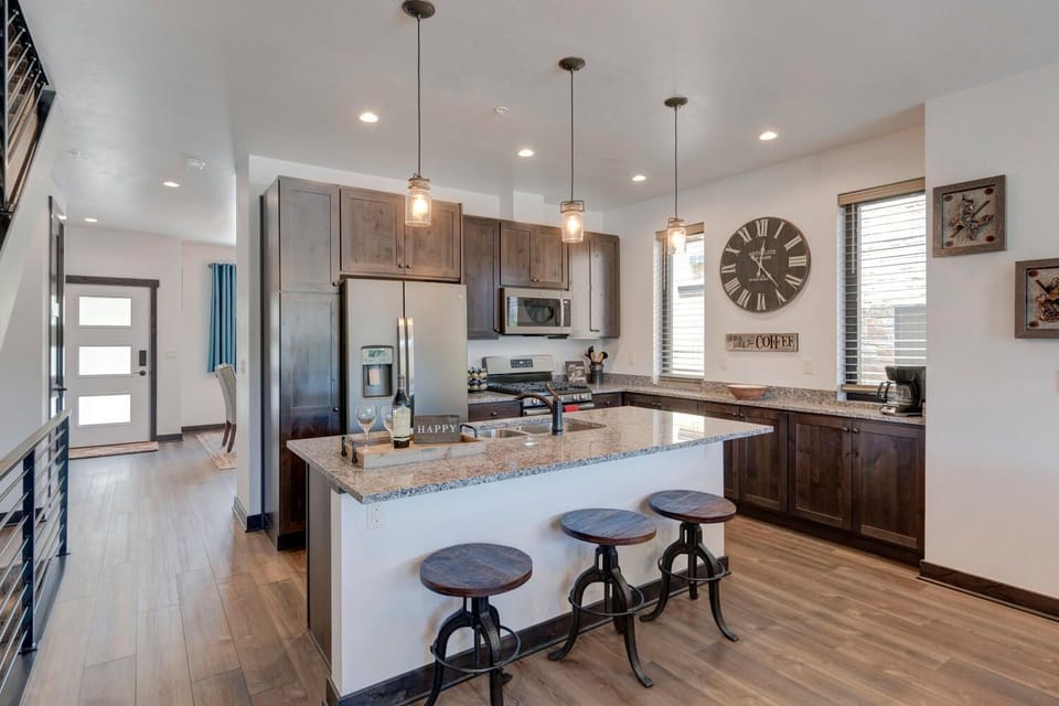 Kitchen with Island, Stools, Refrigerator, Coffee Maker, and Microwave.