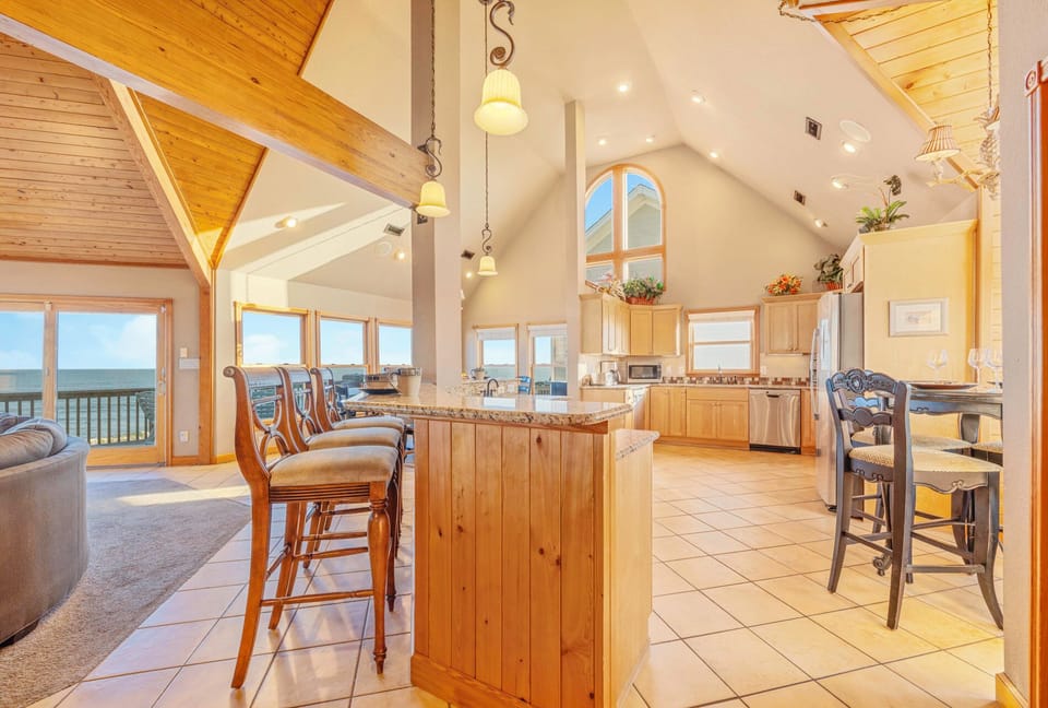 Gather around your spacious kitchen island while soaking in stunning ocean views through floor-to-ceiling windows in this elegant open-concept space.