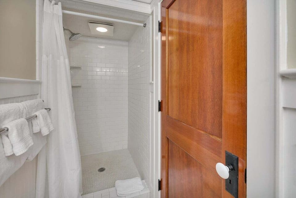 Bathroom with tiled walk-in shower and wood door