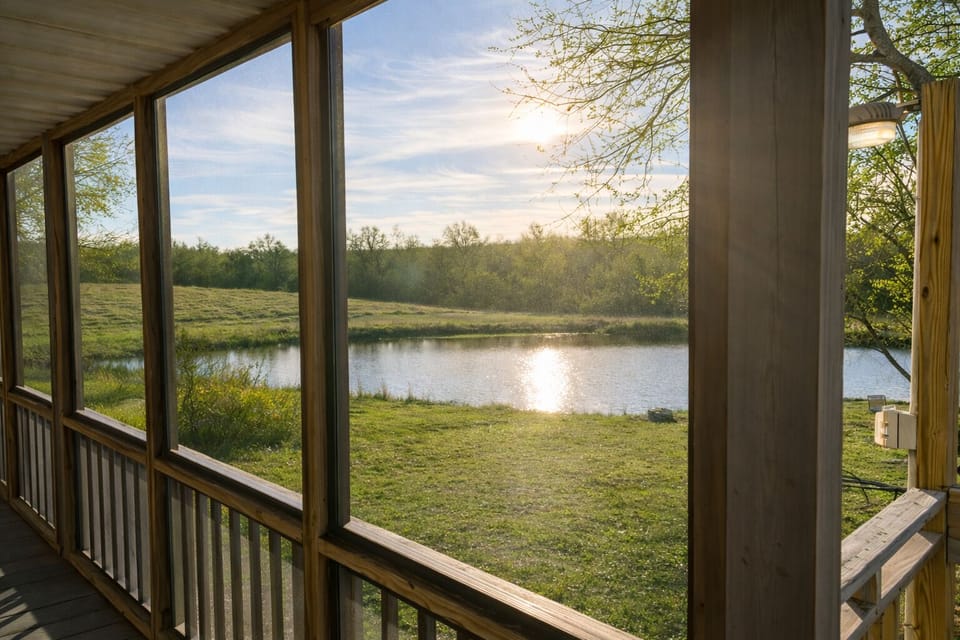 Peaceful pond views from the screened-in deck at Pond View Loft. Enjoy sunrise coffee or sunset reflections overlooking the fishing pond and open country landscape — a perfect spot to relax, unwind, and reconnect with nature.