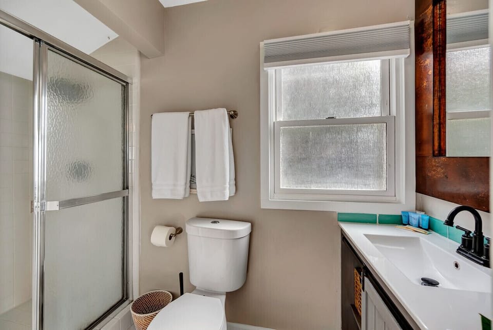 Clean bathroom w/ glass shower doors, fresh towels & natural light