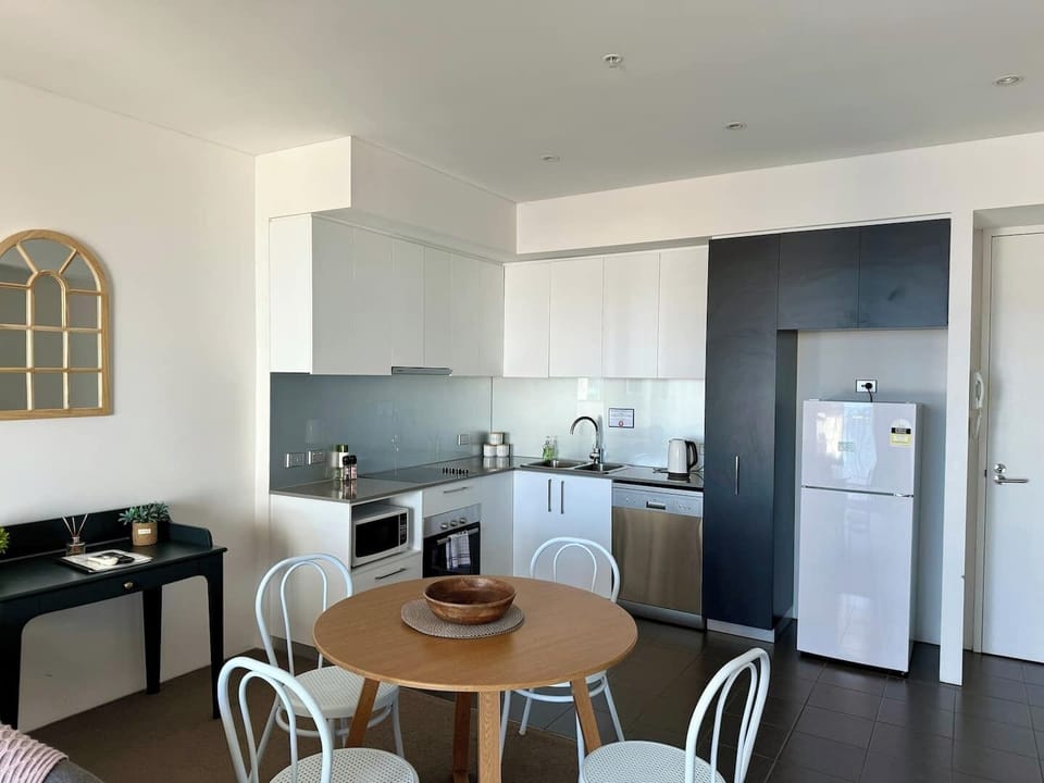 Cook and dine with ease in this modern, fully equipped kitchen featuring sleek cabinetry, essential appliances, and a convenient 4-seater dining table.
