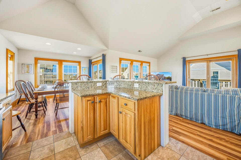 Bright, open kitchen with granite counters and coastal views creates your perfect gathering space for memorable meals.