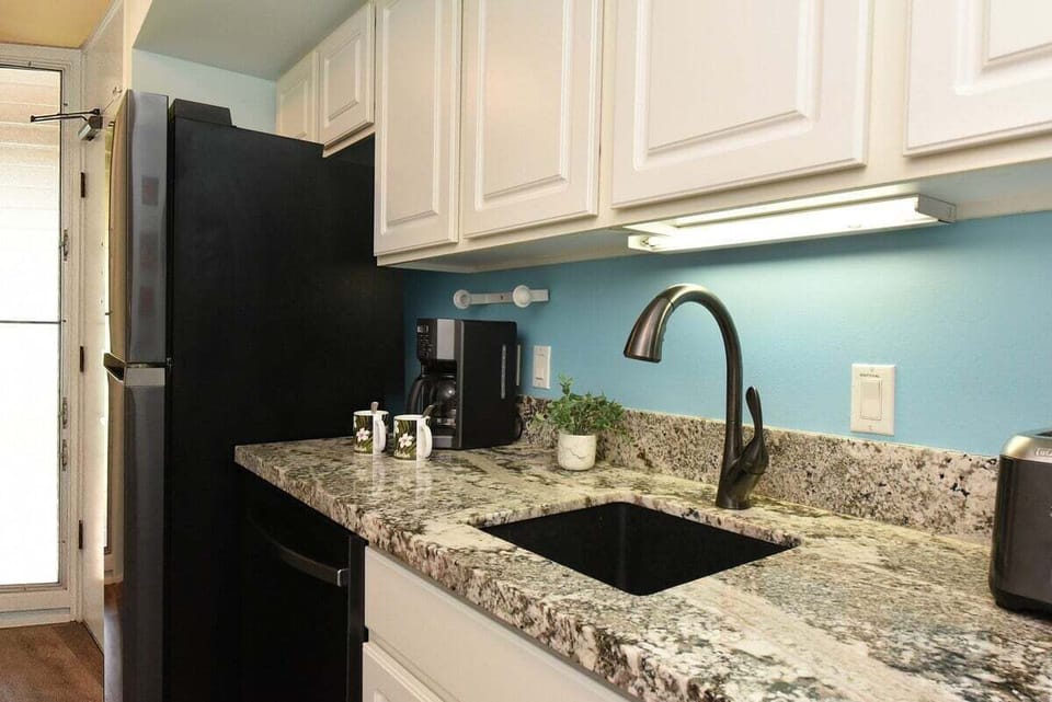 A fully equipped kitchen featuring sleek cabinetry, granite counters, and essential appliances
