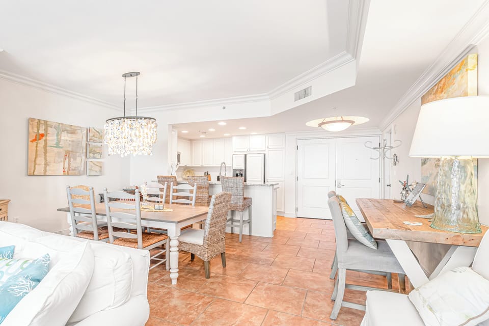 Step into your elegant open living space where chandelier lighting creates warmth above beautiful dining tables and comfortable seating areas.