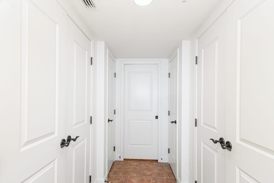 Elegant white hallway with classic wainscoting leads to your private spaces, featuring beautiful tile flooring and sophisticated architectural details throughout.