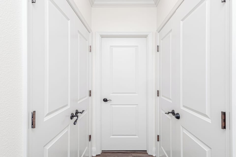 A bright hallway welcomes you with crisp white doors and classic paneled walls, leading to your private spaces with timeless elegance.