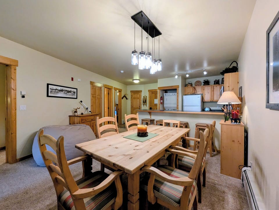 Gather around this rustic wooden table where your group can share meals and memories. The open layout flows into a fully equipped kitchen, making it easy to cook together and stay connected.