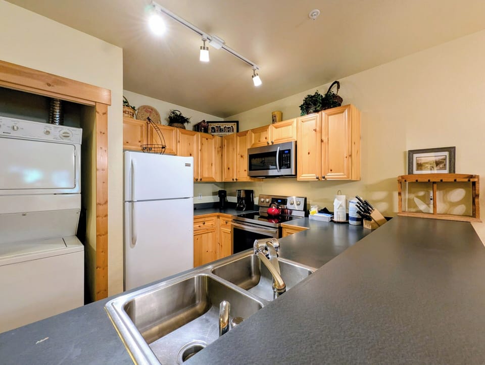 Your fully equipped kitchen features modern appliances and warm wood cabinetry, perfect for preparing meals together during your mountain getaway.