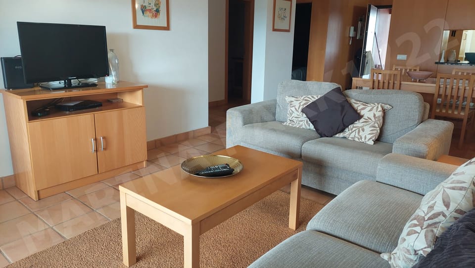 Bright living room with TV, wooden furniture, and access to the balcony at Marina Park apartment, Lagos