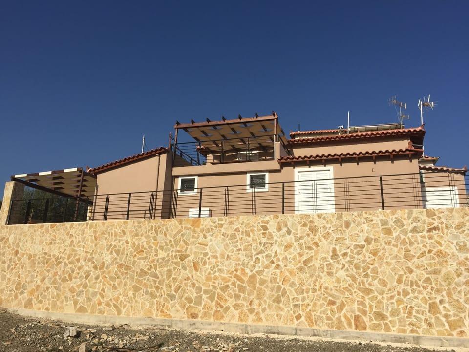 Side of the villa wall showing the upstairs balcony covered with a pergola