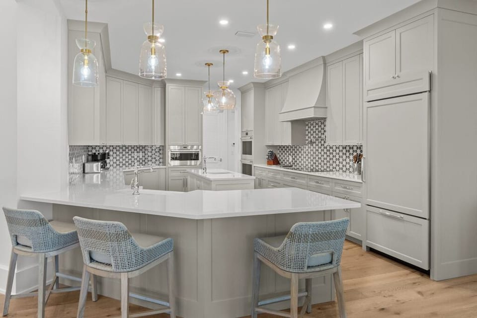 Beautiful white chef's kitchen with a breakfast bar and state-of-the-art appliances.