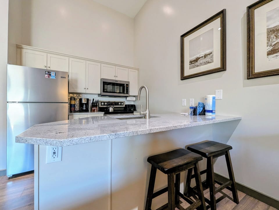 Your fully equipped kitchen features modern appliances and a breakfast bar with cozy seating, perfect for casual meals or morning coffee together.