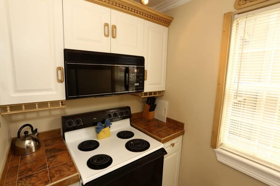 Kitchen equipped with electric stove &amp; microwave.