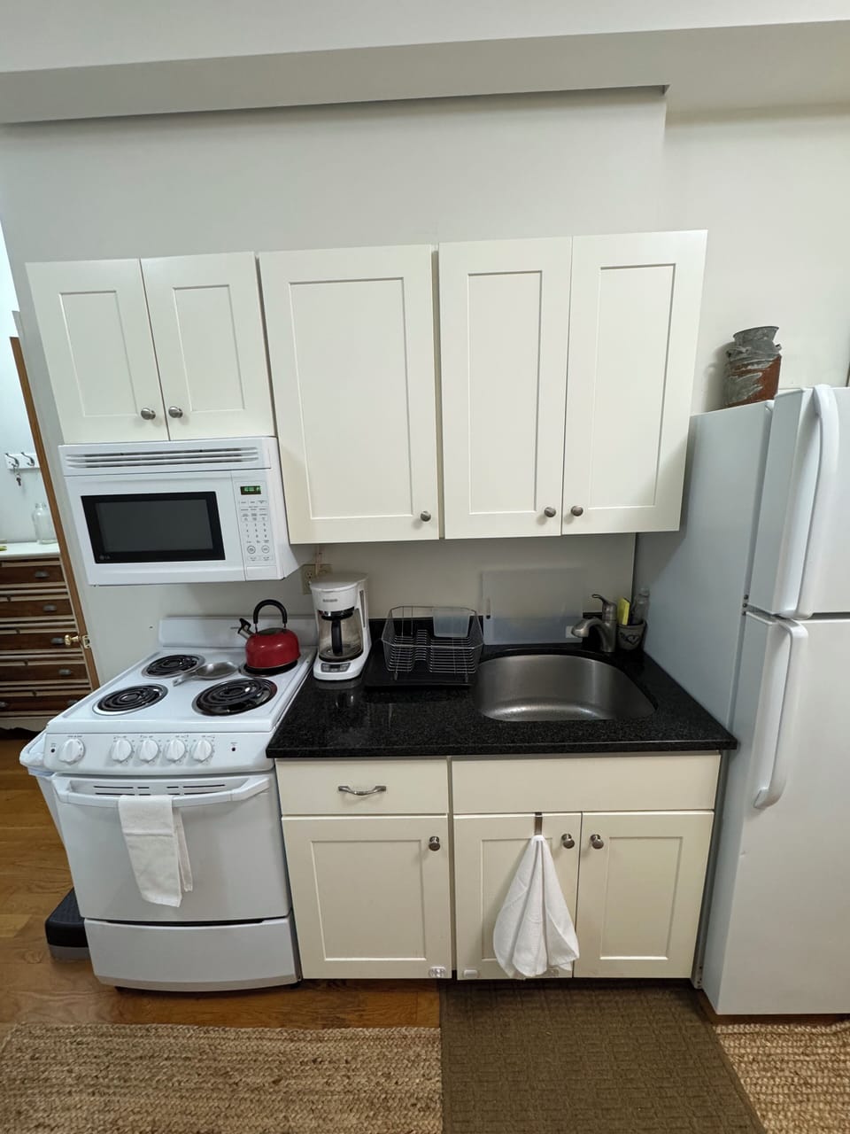 efficient kitchen with microwave, stove, oven, sink and full refrigerator.