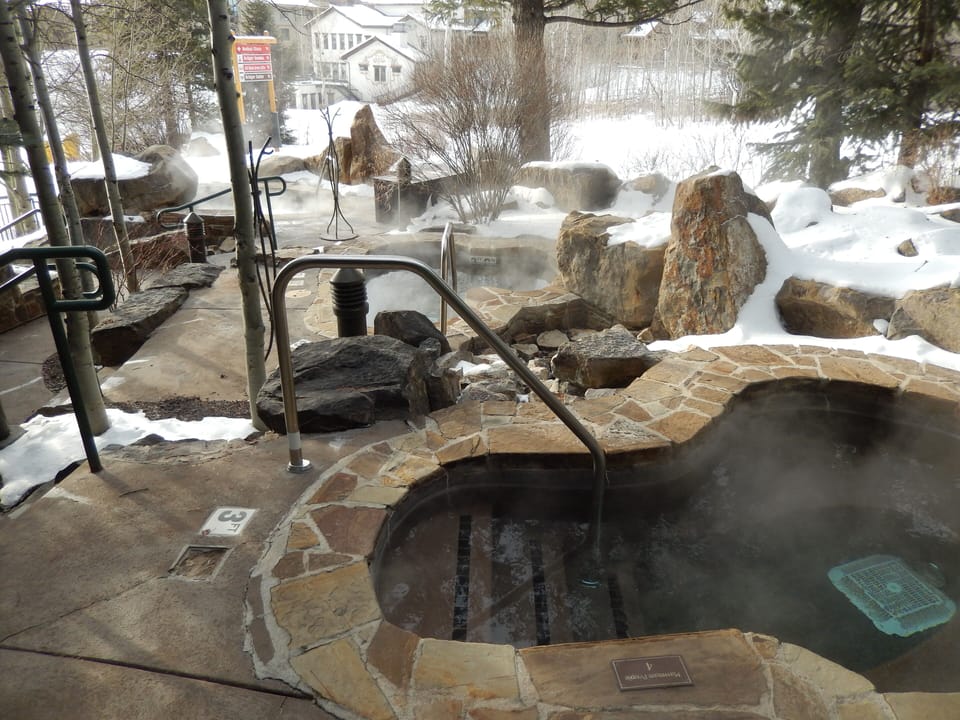 4 Hot tubs among the rocks and evergreens in the Winter