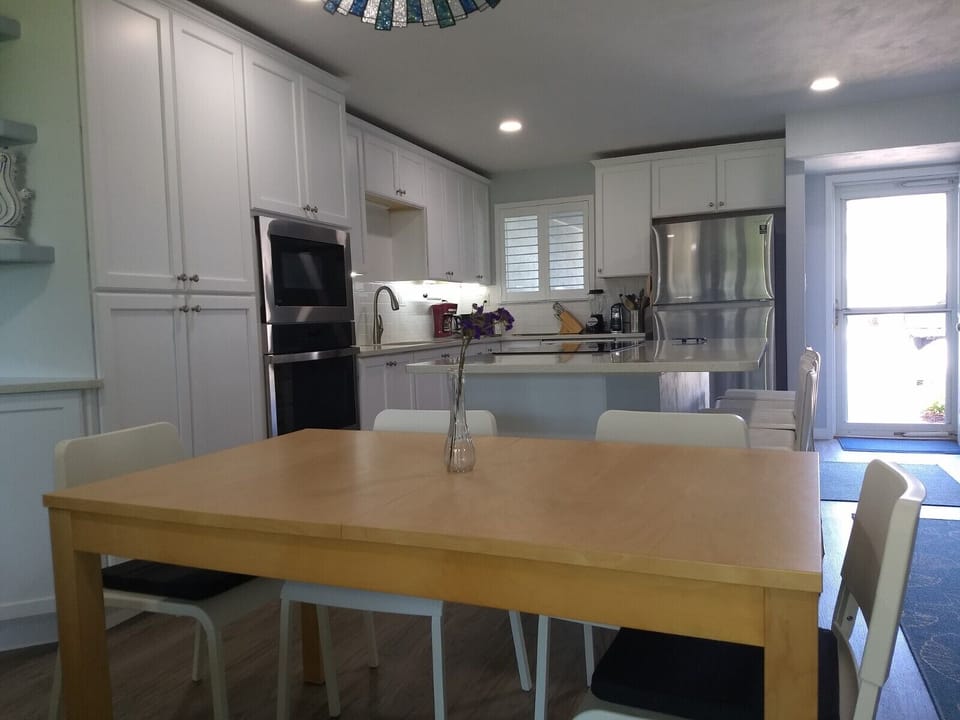 Dining table adjacent to island in kitchen with entry from parking area