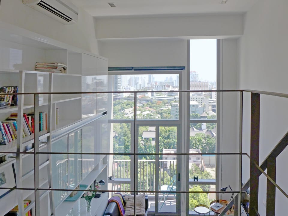 Huge windows overlook leafy compound can be darkened with block out blinds