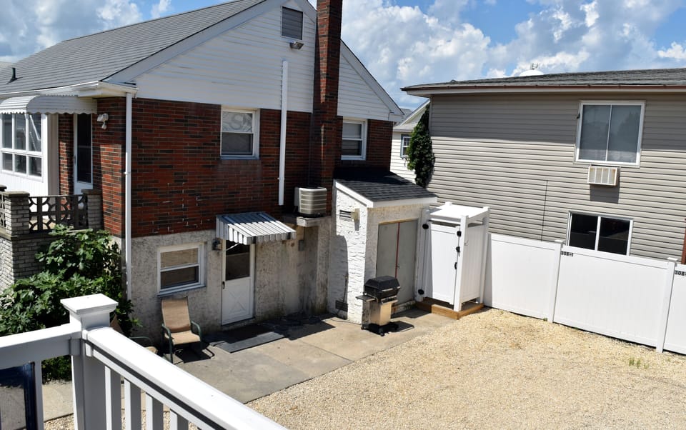 side view of house showing enclosed shower and gas grill
