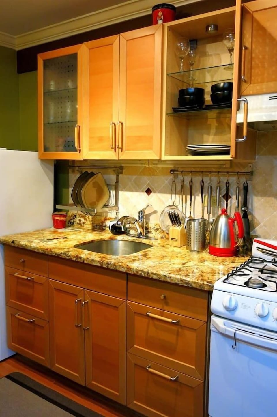 Granite countertop workspace w/ sink, hanging utensils & kettle ready for cooking