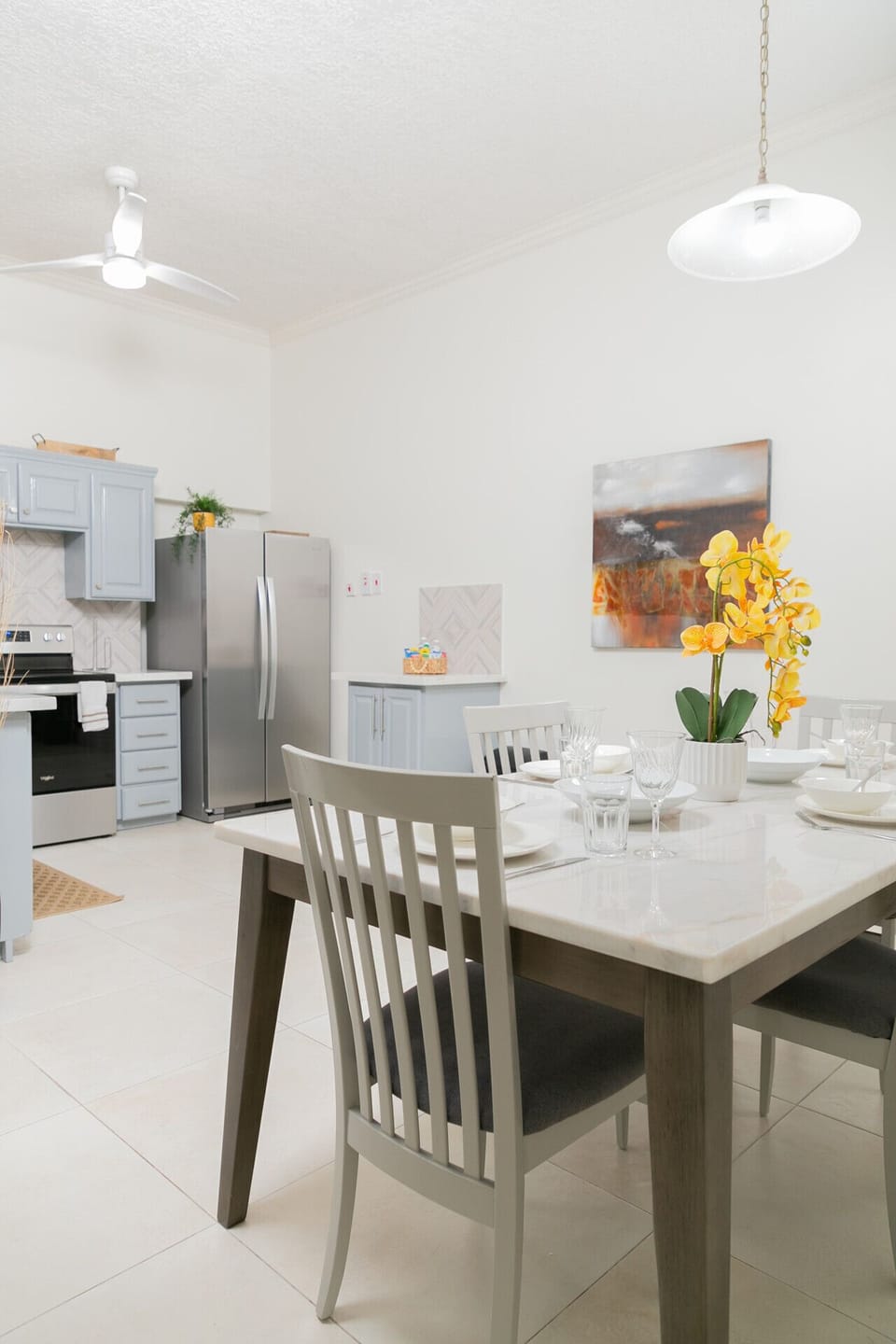 Dining table set for a meal beside the bright modern kitchen.