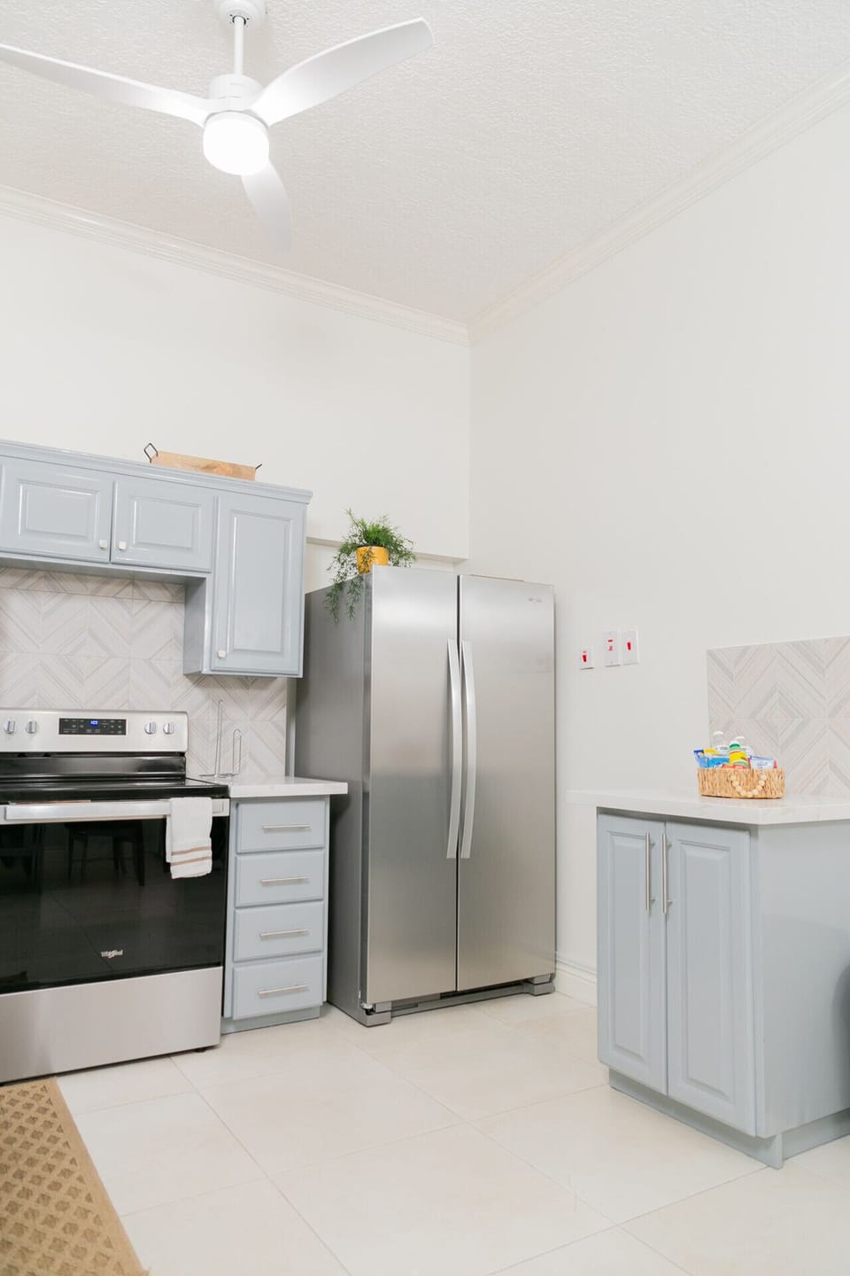 Spacious kitchen corner w/ stainless fridge, gray cabinets & clean modern finishes.