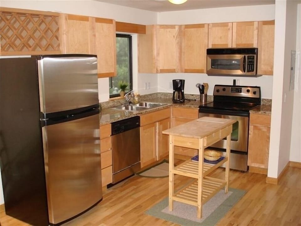 View of Kitchen. Granite counters, stainless steel appliances, wine rack.