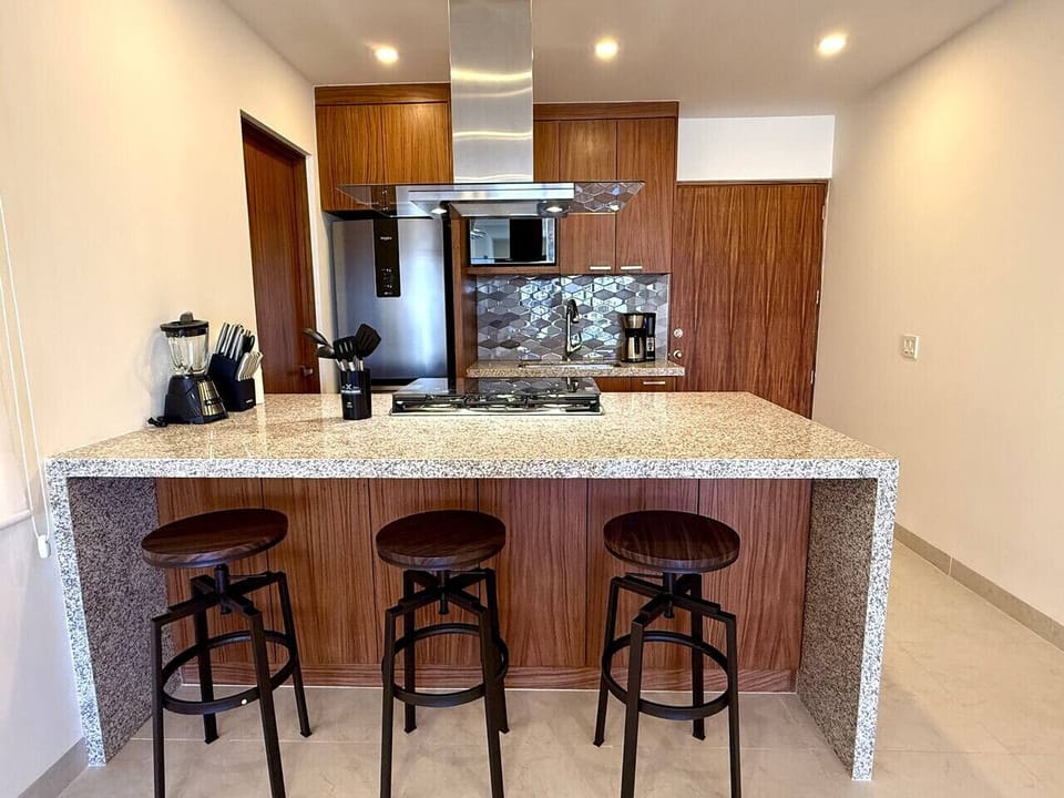 Modern open-concept kitchen with sleek appliances and breakfast bar seating.