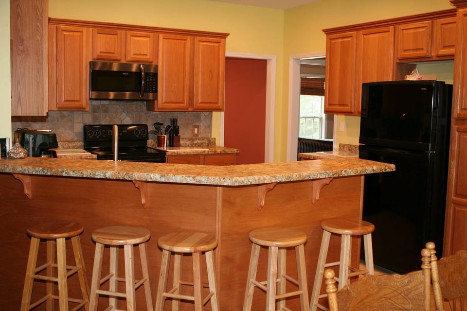 Kitchen counter stools, game room & BR 2 entry viewed from dining area.