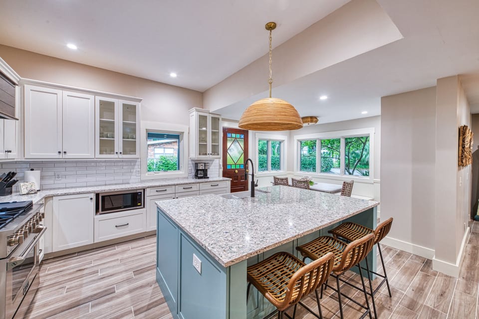 Kitchen with Bay Window and Blue Island – Tabby on 12th - Another look at the kitchen at Tabby on 12th, showing the custom blue island, bay window seating, and plenty of space to prep or gather. Bright, coastal, and built for real vacation living.