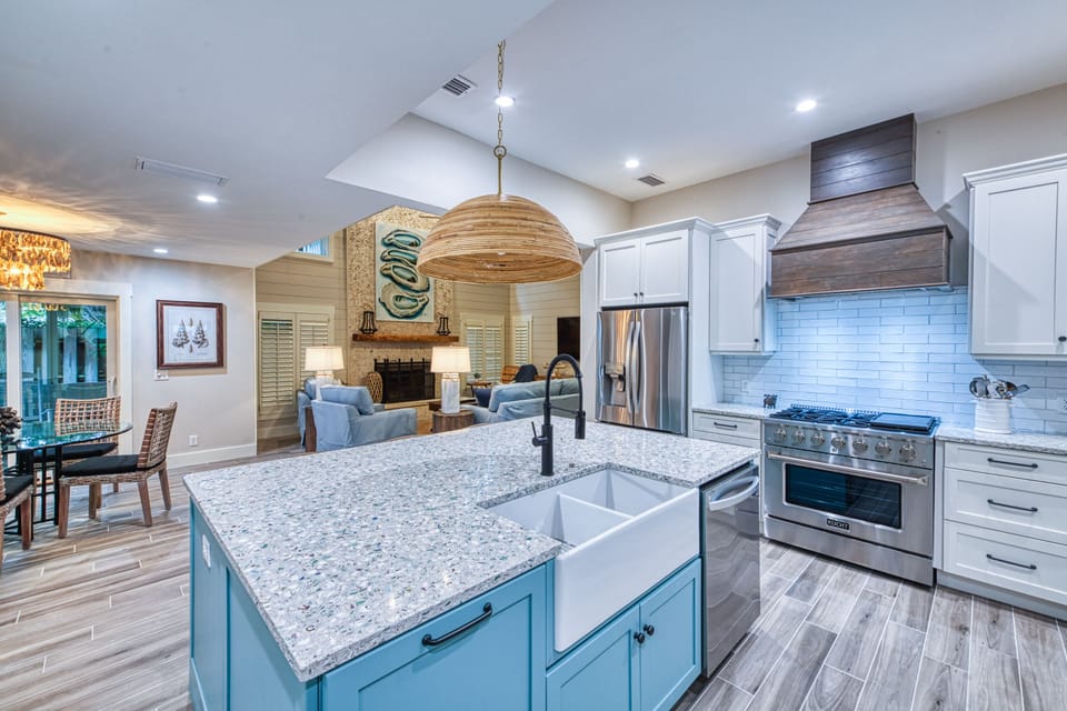 Spacious Kitchen with Farmhouse Sink and Open Living Layout - Tabby on 12th’s kitchen anchors the home with custom cabinetry, a farmhouse sink, granite countertops, and open sightlines to the dining and living rooms. It’s perfect for prepping a beach day picnic or gathering for a seafood dinner after exploring St. Simons Island.