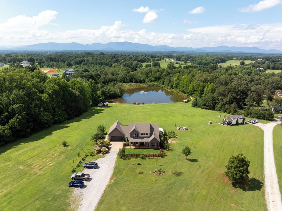 Aerial view of Uproot Farms, the pond, open acreage, and mountain horizon.