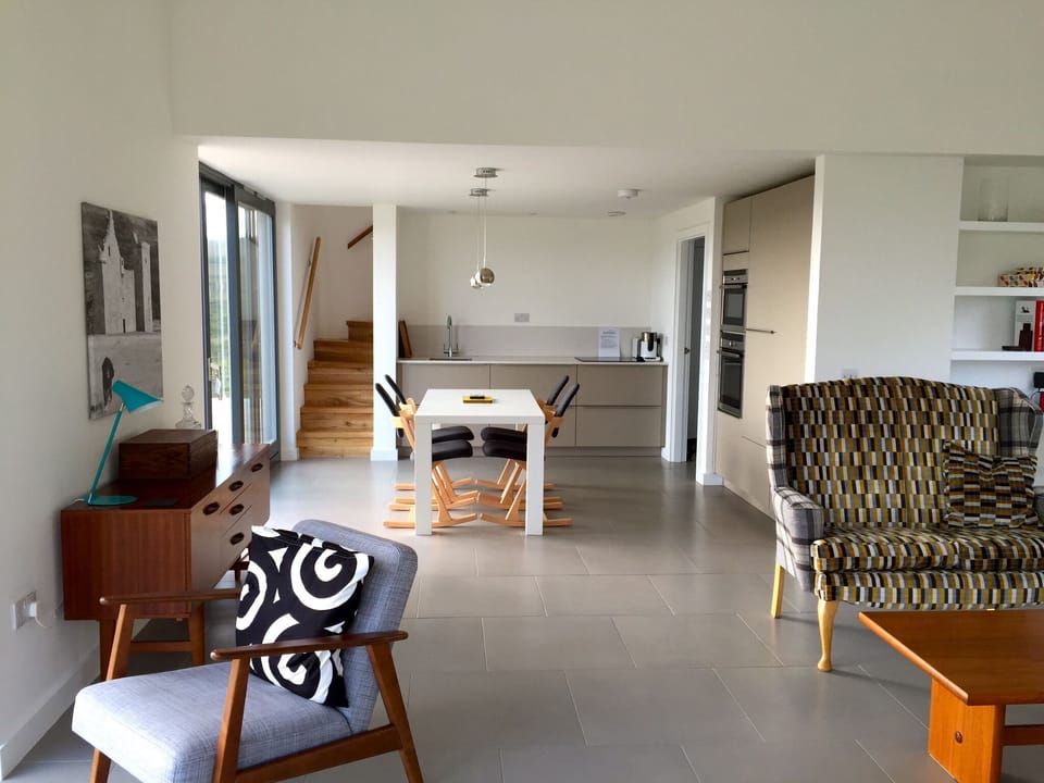 Open plan kitchen with table in front of panoramic windows.