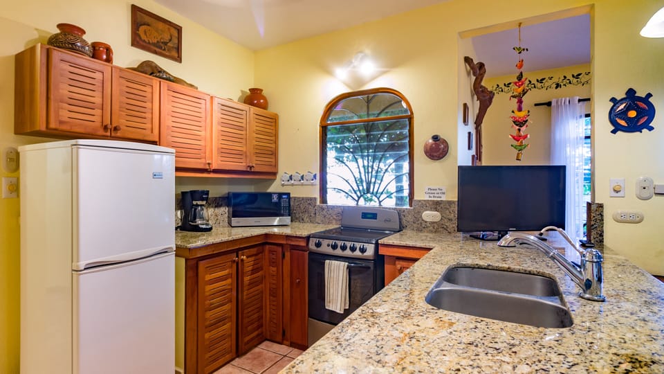 Kitchen has granite counters and teak cabinets.