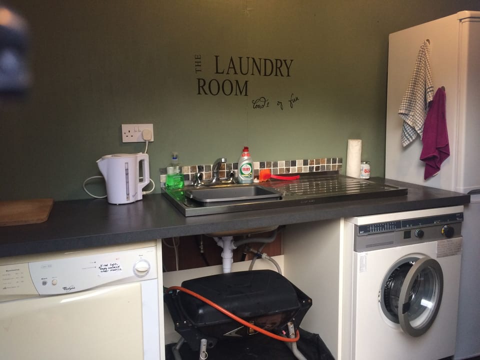 Outside separate laundry room with washer, dryer, fridge freezer and gas grill. 