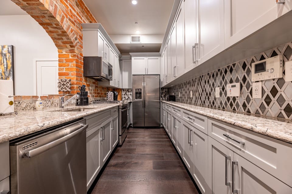 Galley-style, fully equipped kitchen with an open flow to the living/dining area. Stocked with essentials from mixing bowls to wine glasses, featuring stainless steel appliances, stone countertops, and a tile backsplash for a luxurious feel!