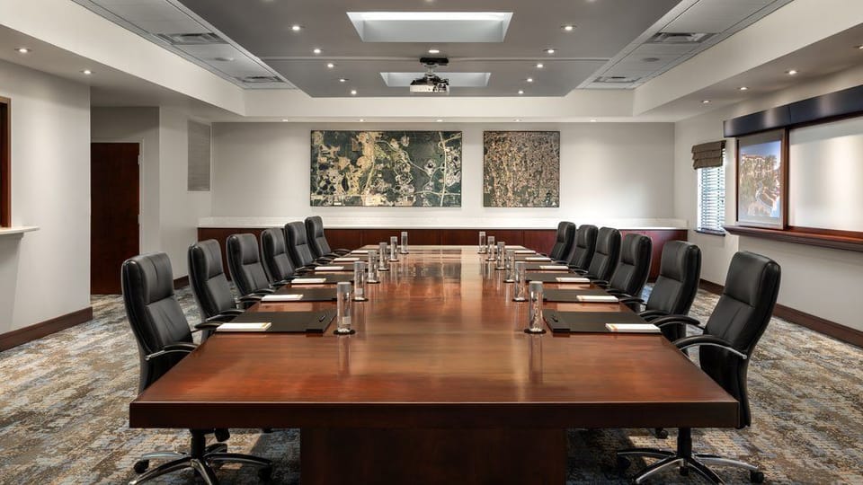 Gather around the sleek conference table, perfect for meetings and discussions, bathed in warm, inviting light.