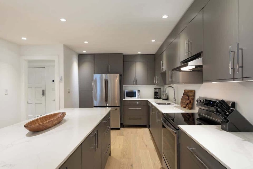 - Modern kitchen with sleek cabinetry and stainless-steel finish  
- Bright lighting enhances the clean design and spacious island  
- Perfect space for gourmet cooking after a day on Whistler slopes  