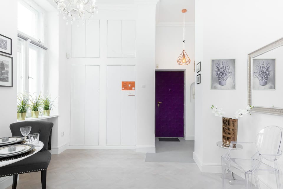 Elegant and modern studio with carefully selected decorative details, stylish dining area, white sofa, and functionall kitchenette.
