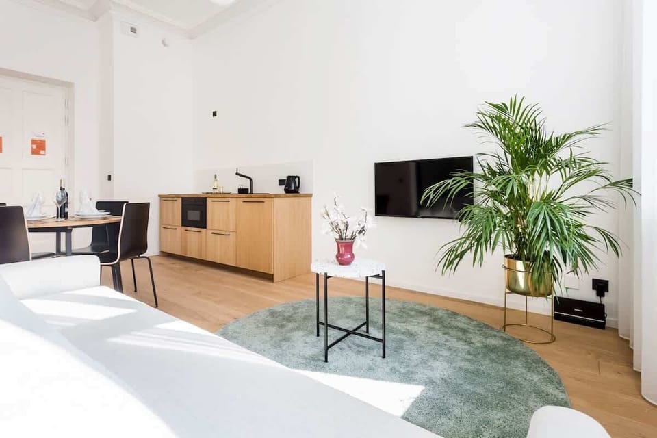 White and wooden living space with capacious cabinet and wardrobe, functional dining area, and comfortable double sofa bed.