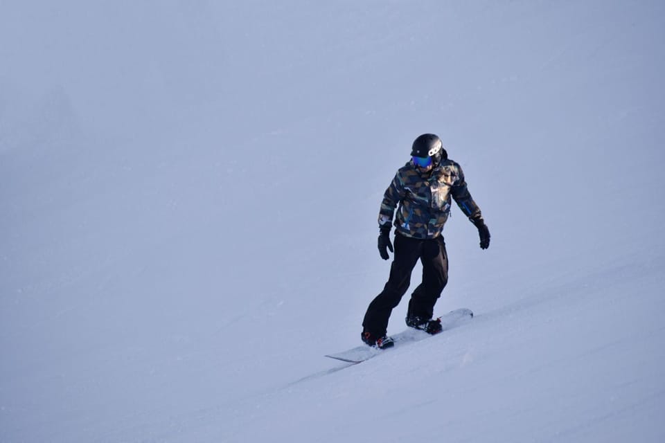 A snowboarder carves down the slopes of Plagne Center, part of the vast Paradiski ski area in the French Alps.