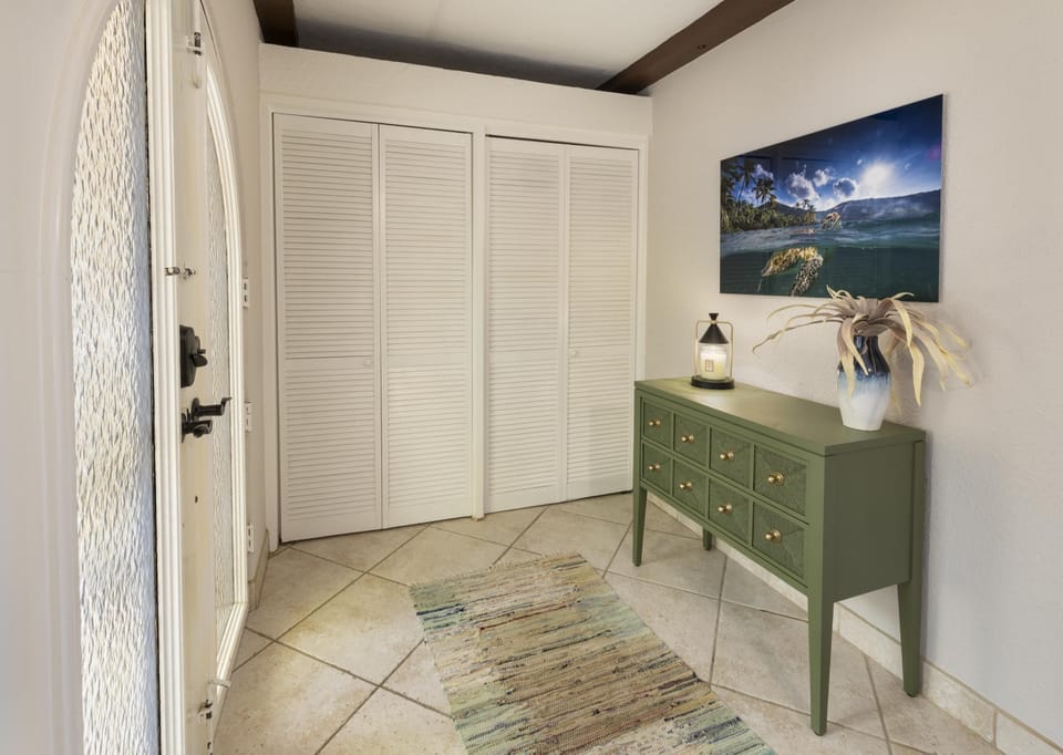 Entryway with green console table and coastal wall art.