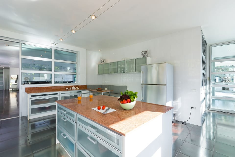 Kitchen with island, large fridge, microwave, kettle, wine glasses and more