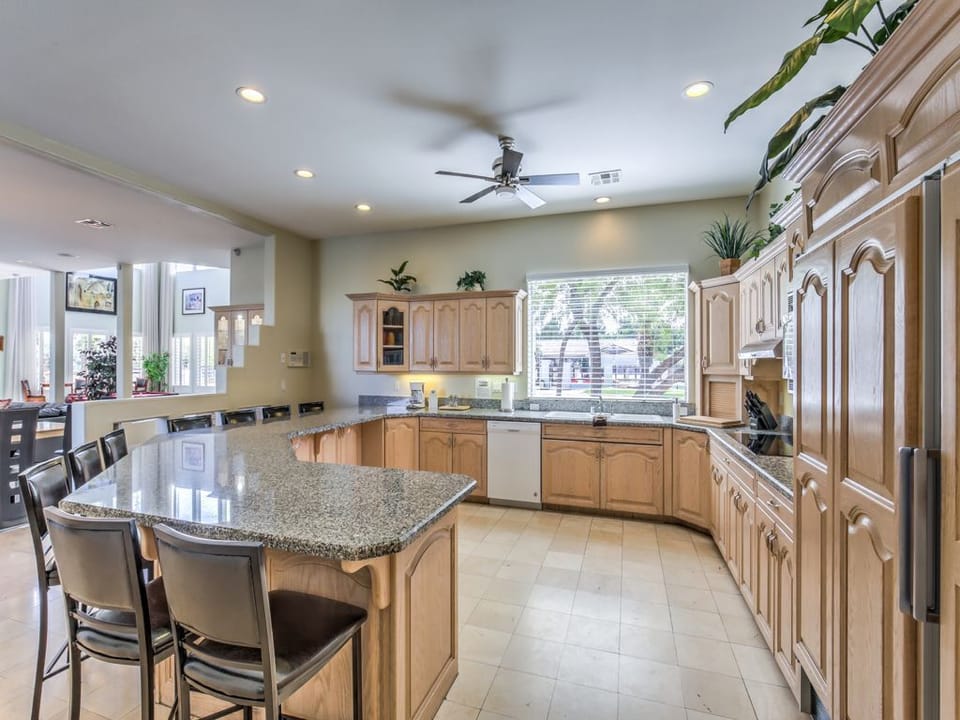 Stocked gourmet kitchen has 5-burner stove top and large extra-deep bar seats 9