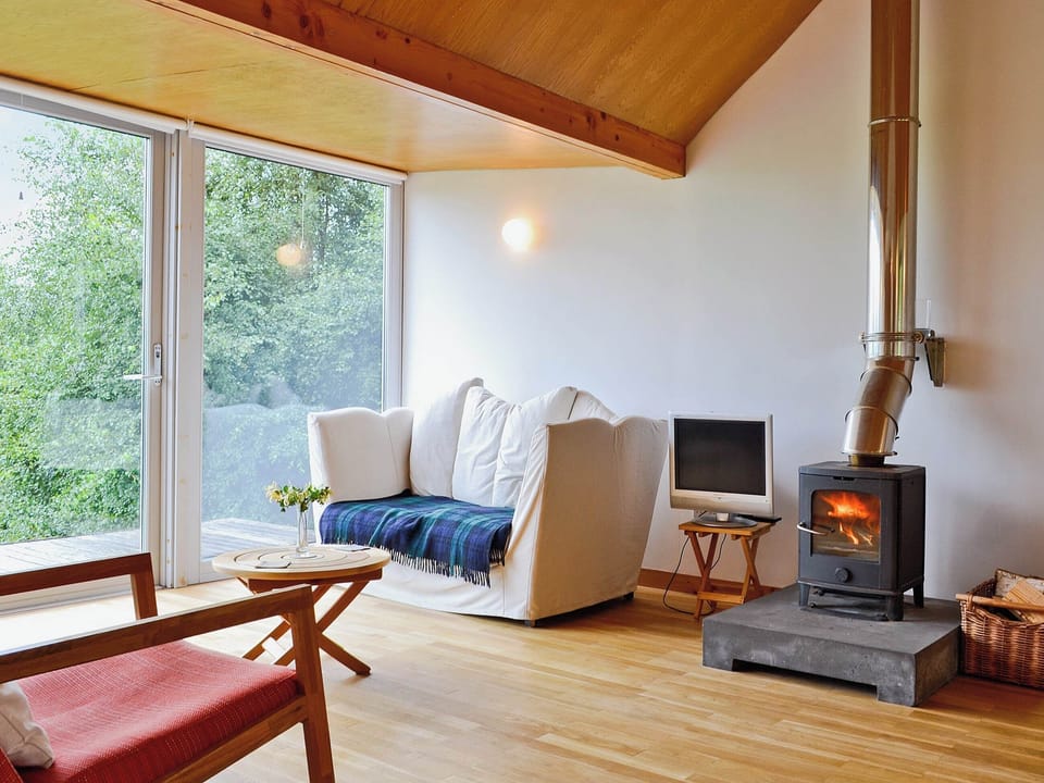 The woodburning stove makes the wood-floored, wood-celienged living area feel warm and cosy | West Bothy at Cluain Ghrianach, Laga, near Acharacle