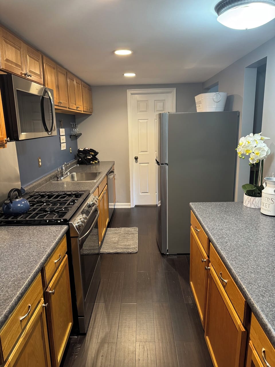 Inside view of the kitchen area with stove, microwave, refrigerator and more.