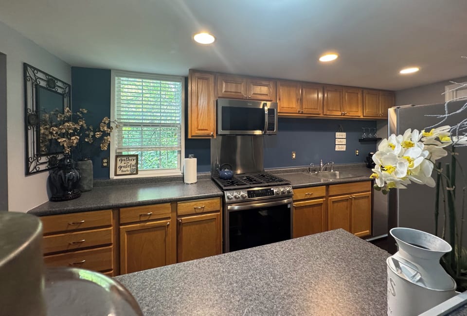 Expanded view of the kitchen area with stove and microwave and counter space.