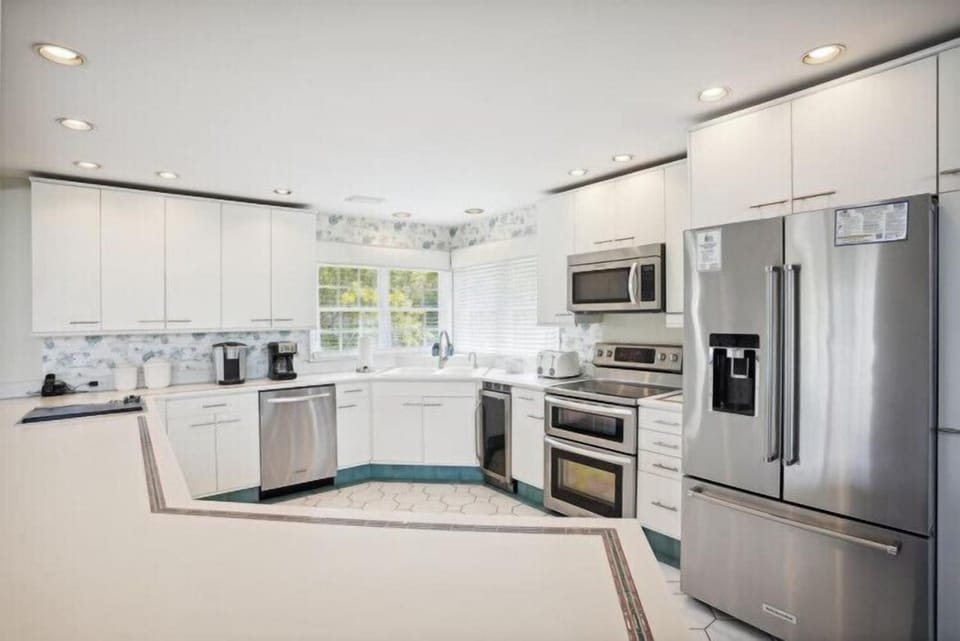 Step into your fully-equipped kitchen where stainless appliances and bright white cabinetry create the perfect space for preparing memorable meals during your stay.