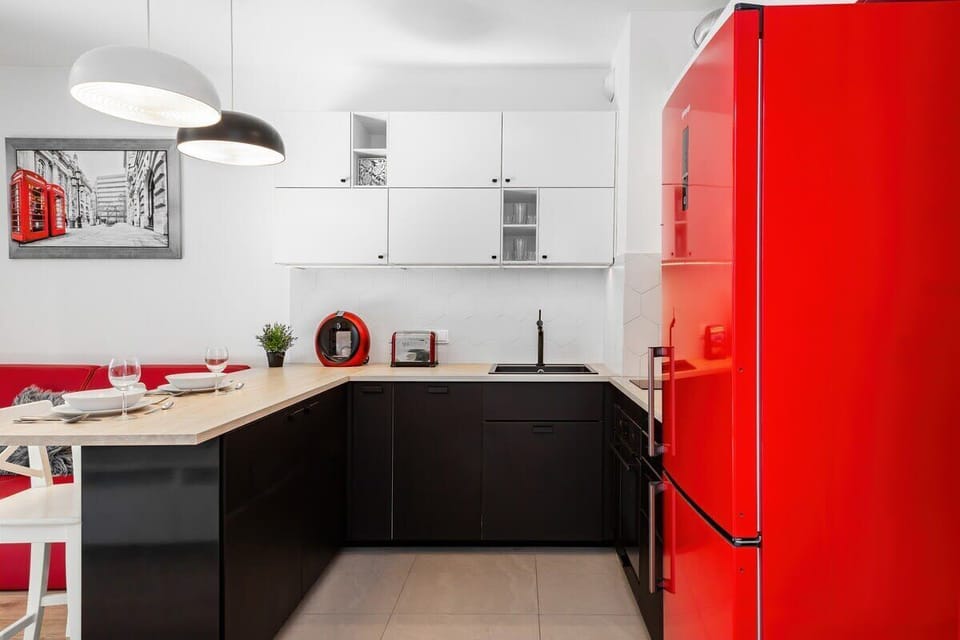 Functional and elegant kitchen with white cabinets, black countertops, and red accents.