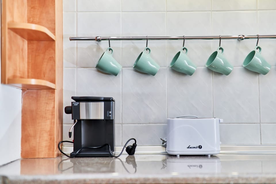Aesthetic separate kitchen with a modern coffee machine, a functional toaster, and stylish green mugs.